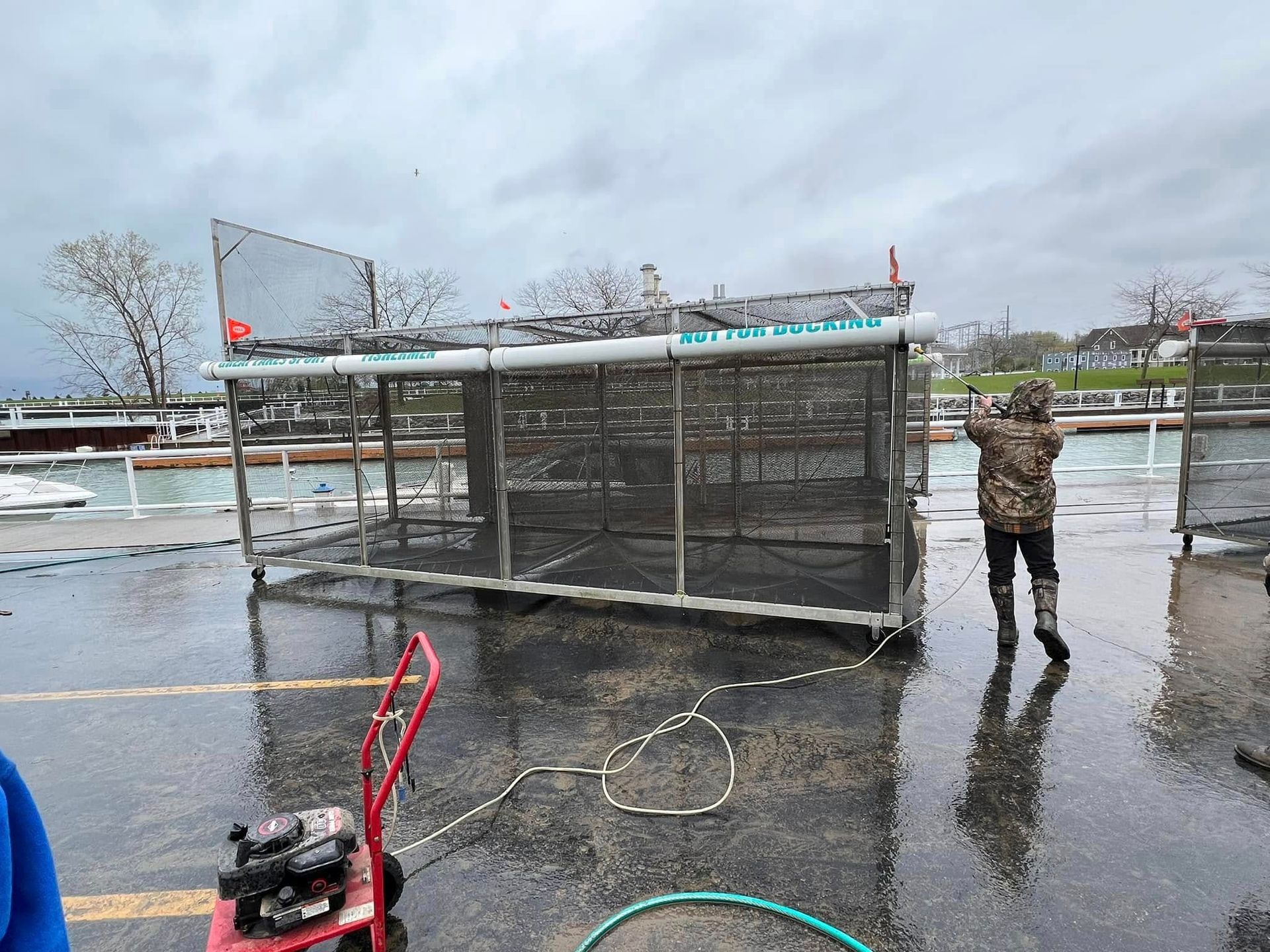 A man is standing in front of a cage in the rain.