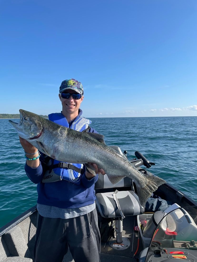 A man is holding a large fish on a boat in the water.