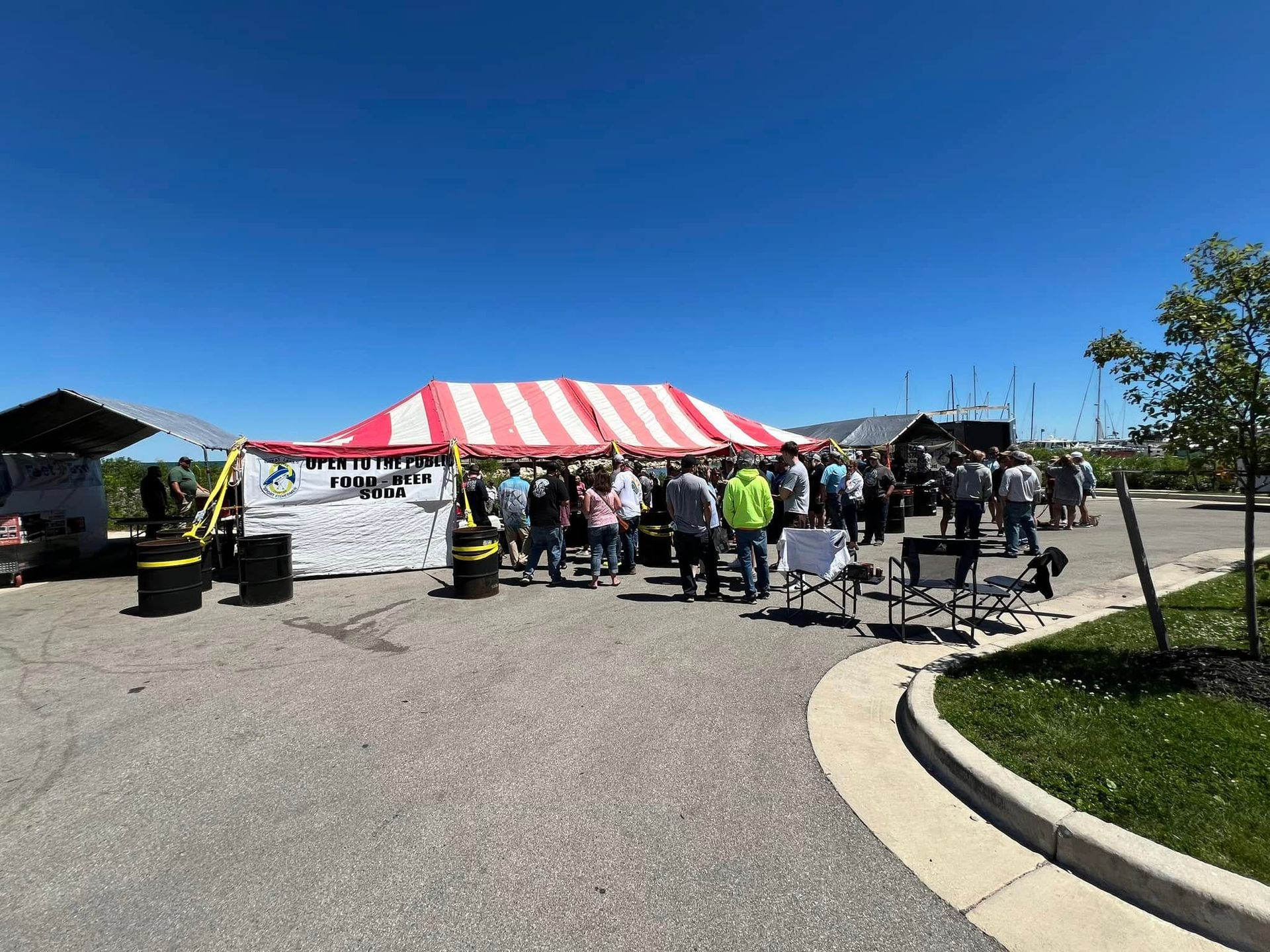 A group of people are standing in front of a red and white tent.