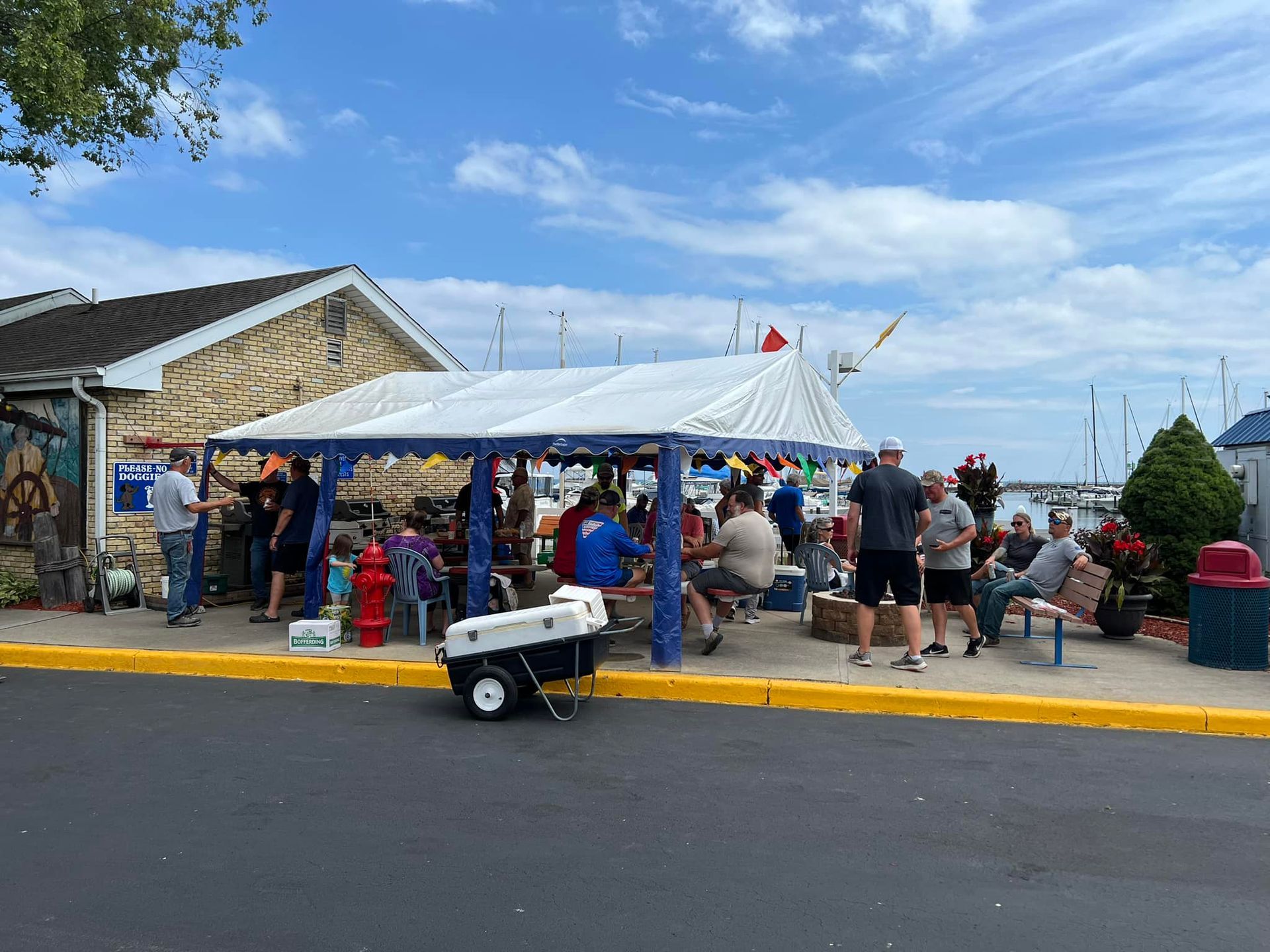 A group of people are sitting under a tent on the side of the road.