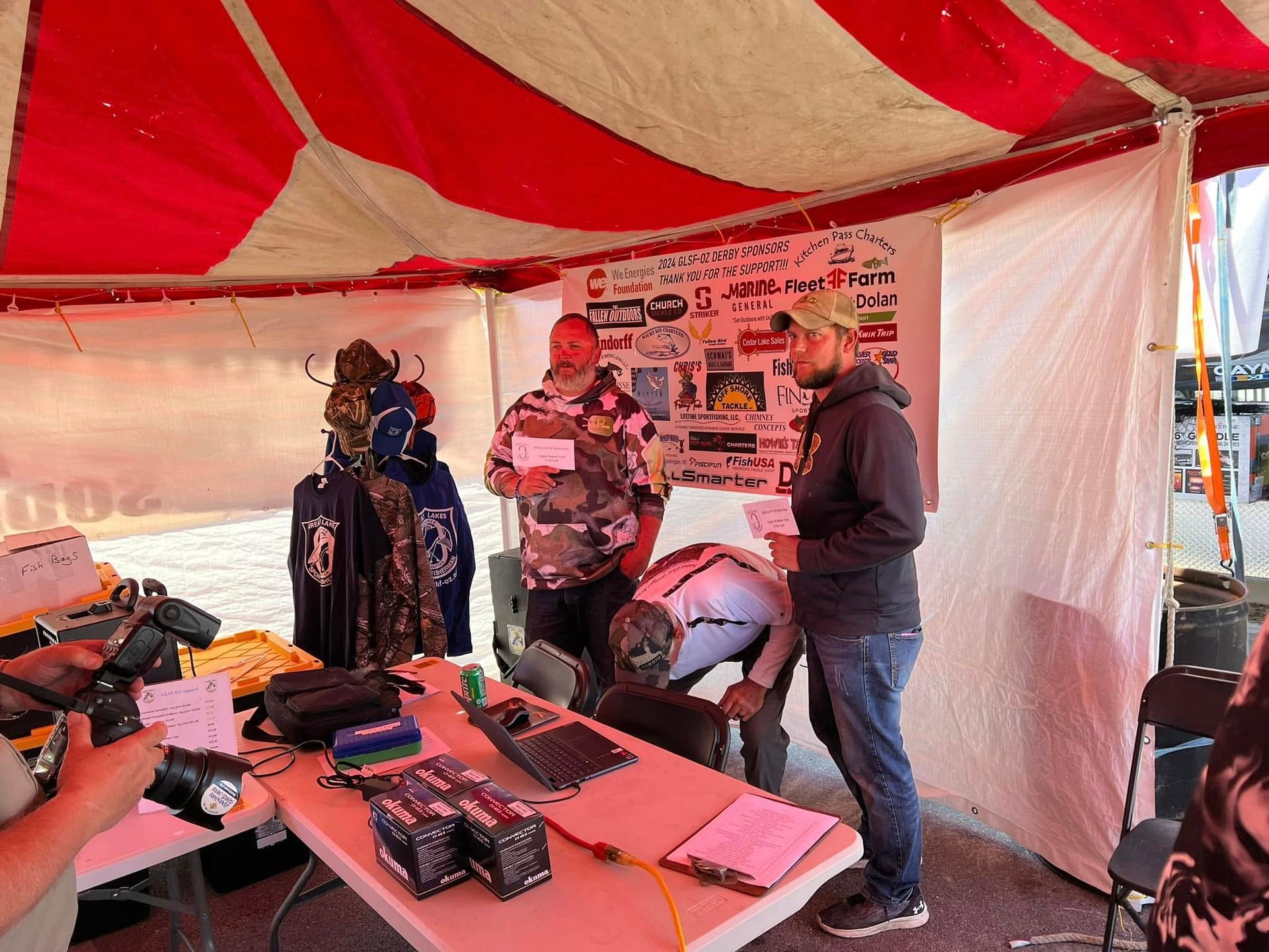 A group of people are standing around a table under a tent.