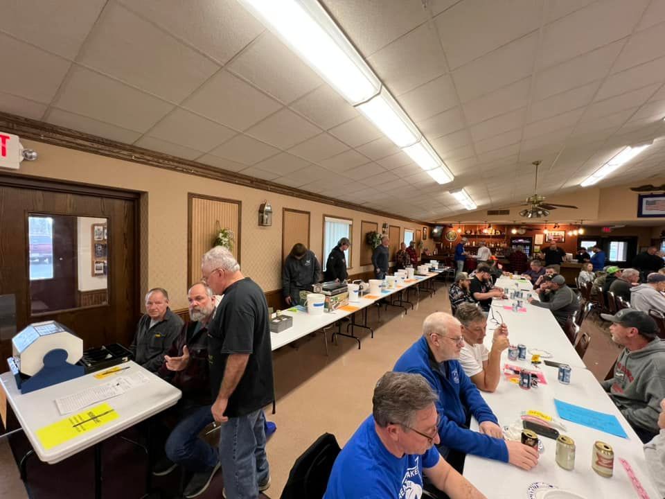A group of men are sitting at long tables in a room.