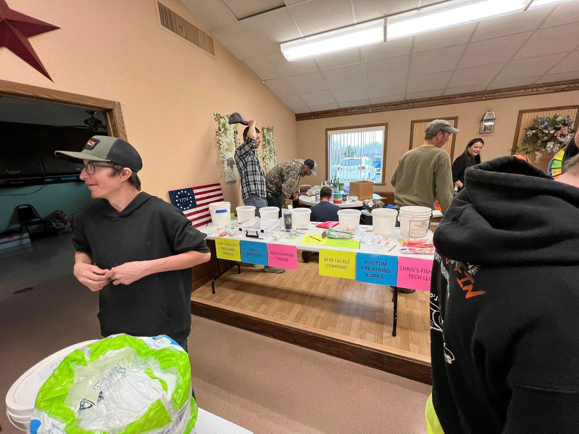 A group of people are standing around tables in a room.
