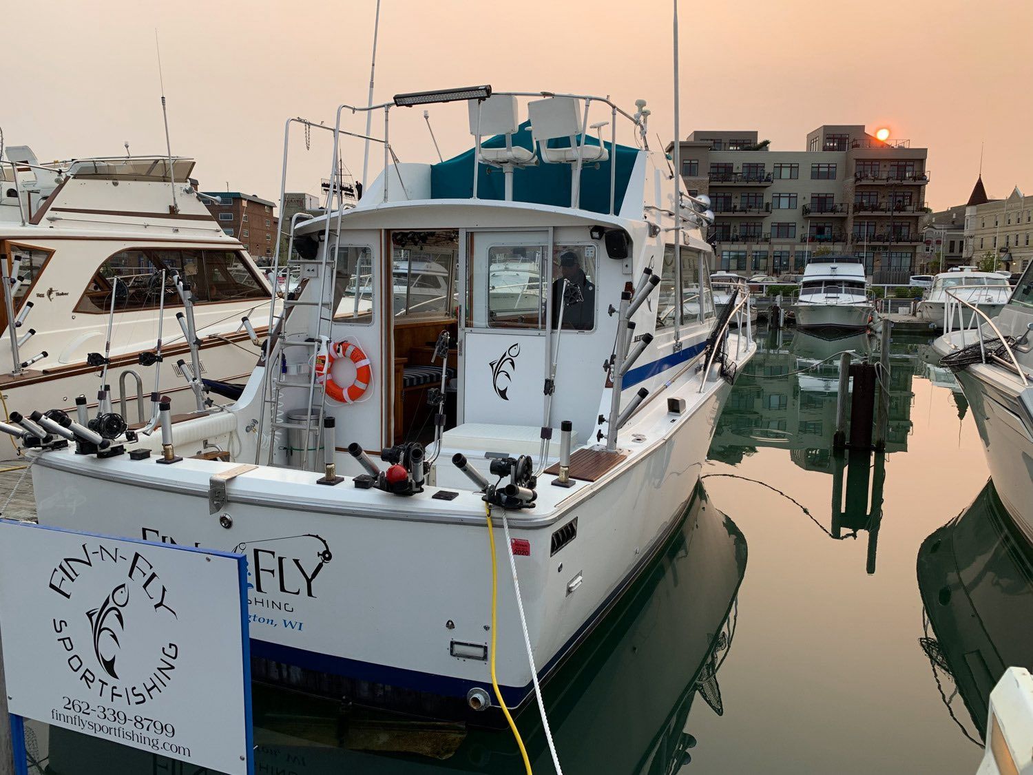 A white boat with the word fly on the side is docked in a marina.