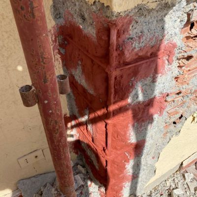 Un muro di mattoni con un tubo rosso al centro.