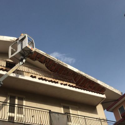 Un edificio con un balcone e una gru in cima.