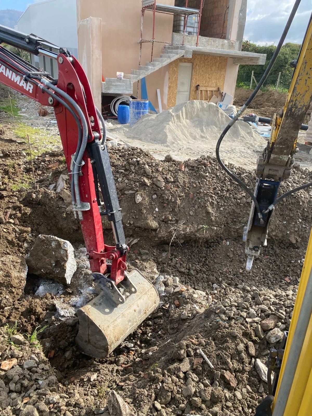 Un escavatore rosso sta scavando una buca nel terreno.