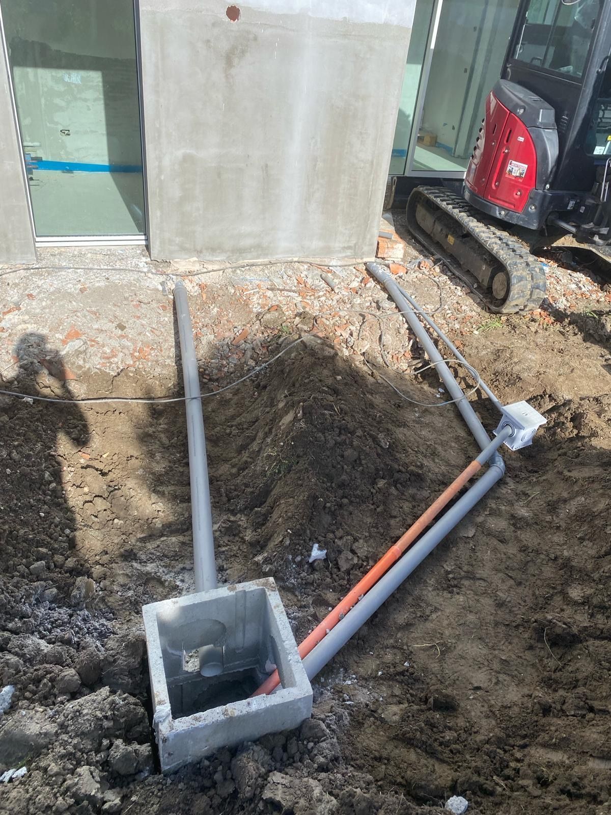 Un cantiere con una scatola di cemento e tubi nel terreno.