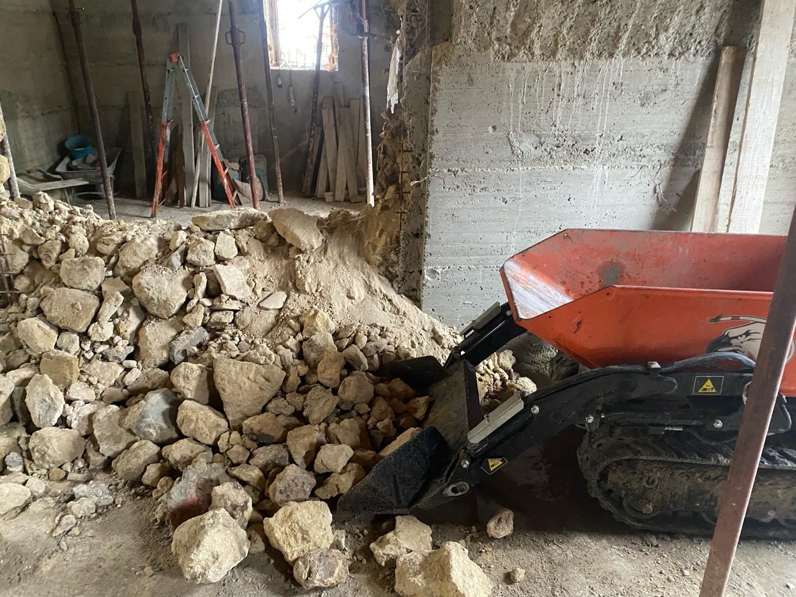 Una carriola è parcheggiata in una stanza accanto a un mucchio di pietre.