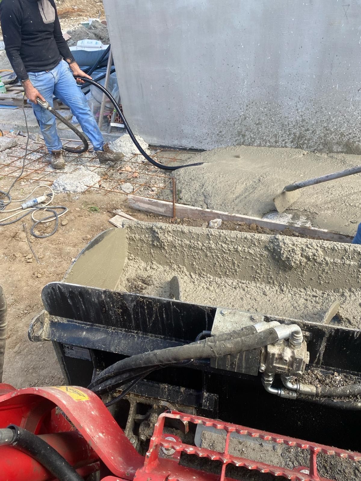 Un uomo sta versando cemento in un secchio in un cantiere edile.
