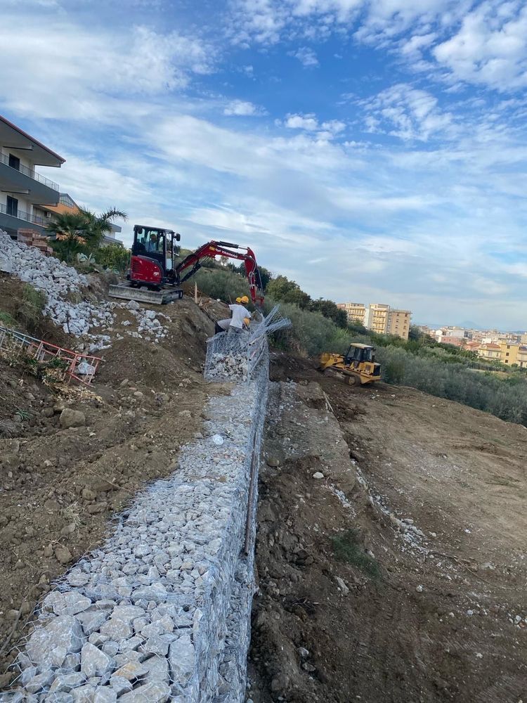 Un escavatore rosso sta lavorando su una parete rocciosa.