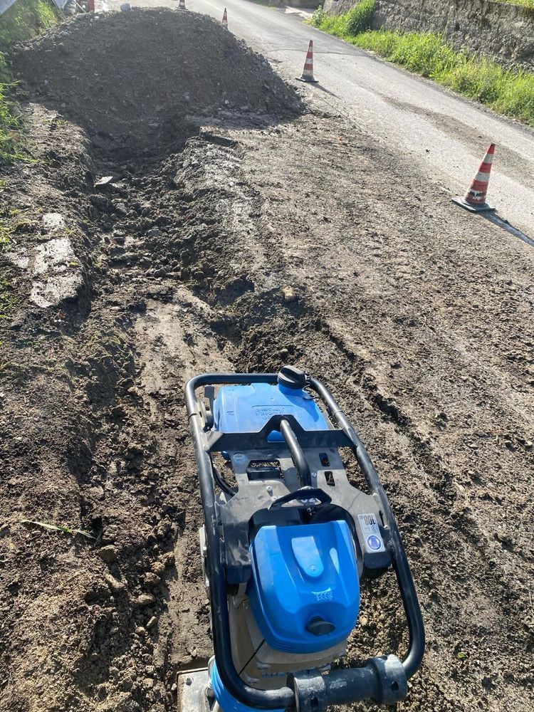 Una macchina blu è parcheggiata sul ciglio di una strada sterrata.