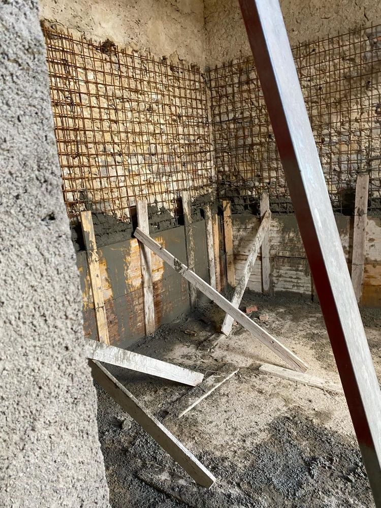 Una stanza con un muro di mattoni e un muro di cemento in costruzione.