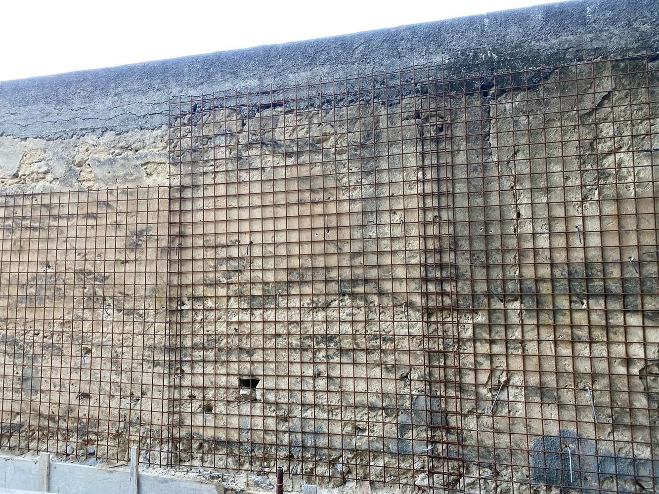 Un primo piano di un muro di mattoni con una rete metallica.