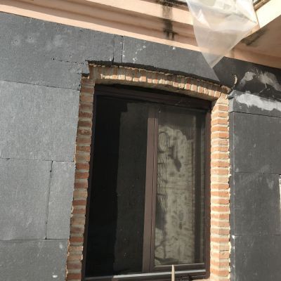 Un muro di mattoni con una finestra e un sacchetto di plastica appeso