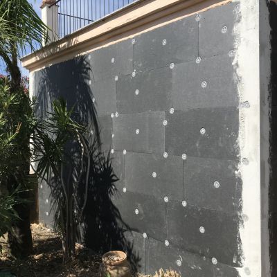 Un muro nero con dei puntini bianchi è circondato da alberi.