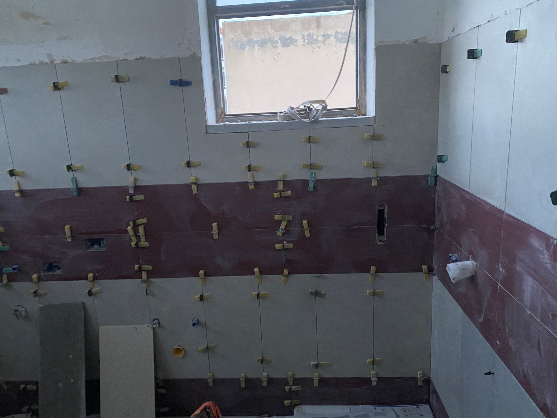 Un bagno in costruzione con una finestra e piastrelle sul muro