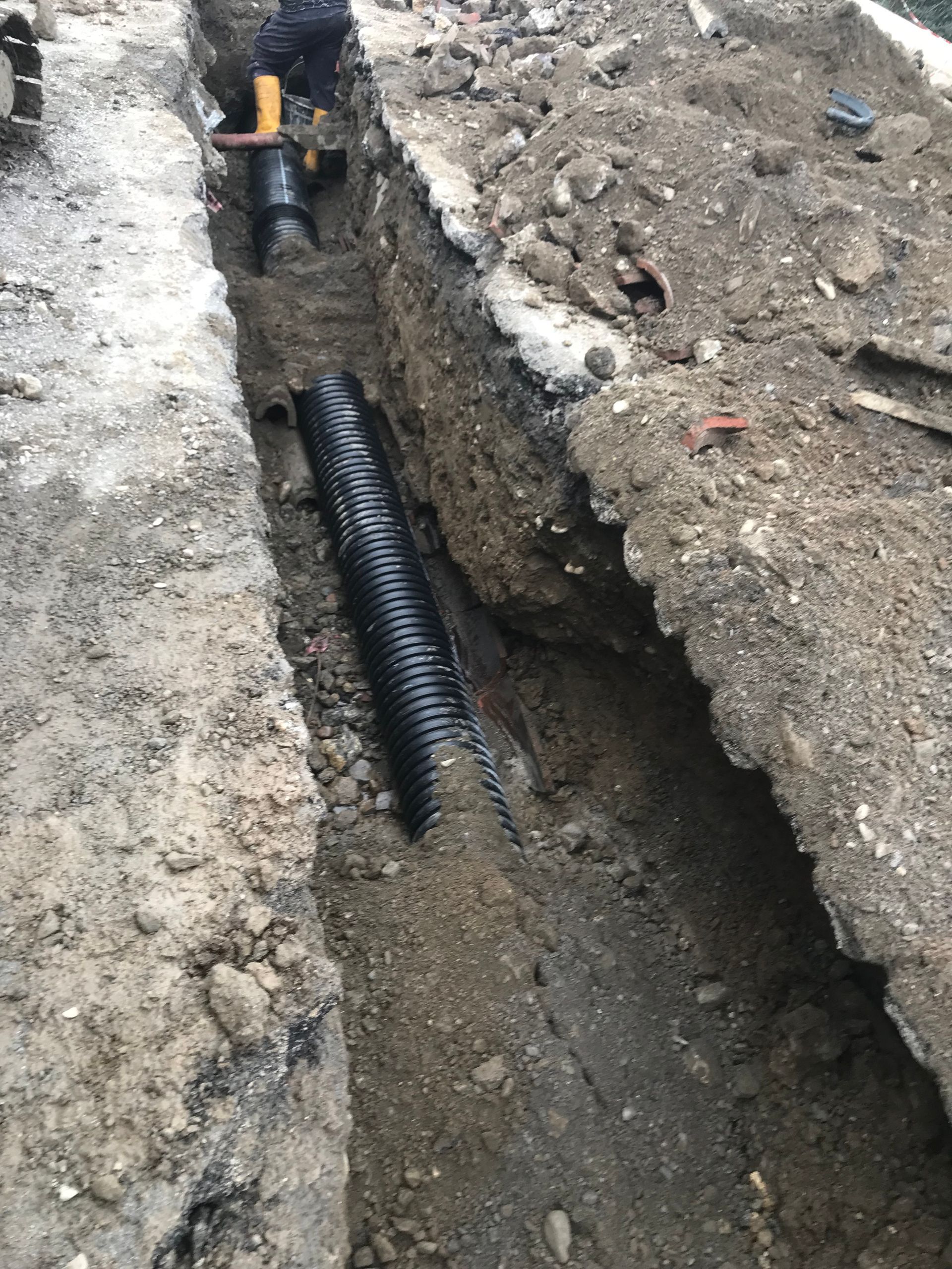 Un uomo sta scavando una buca nel terreno per installare un tubo.