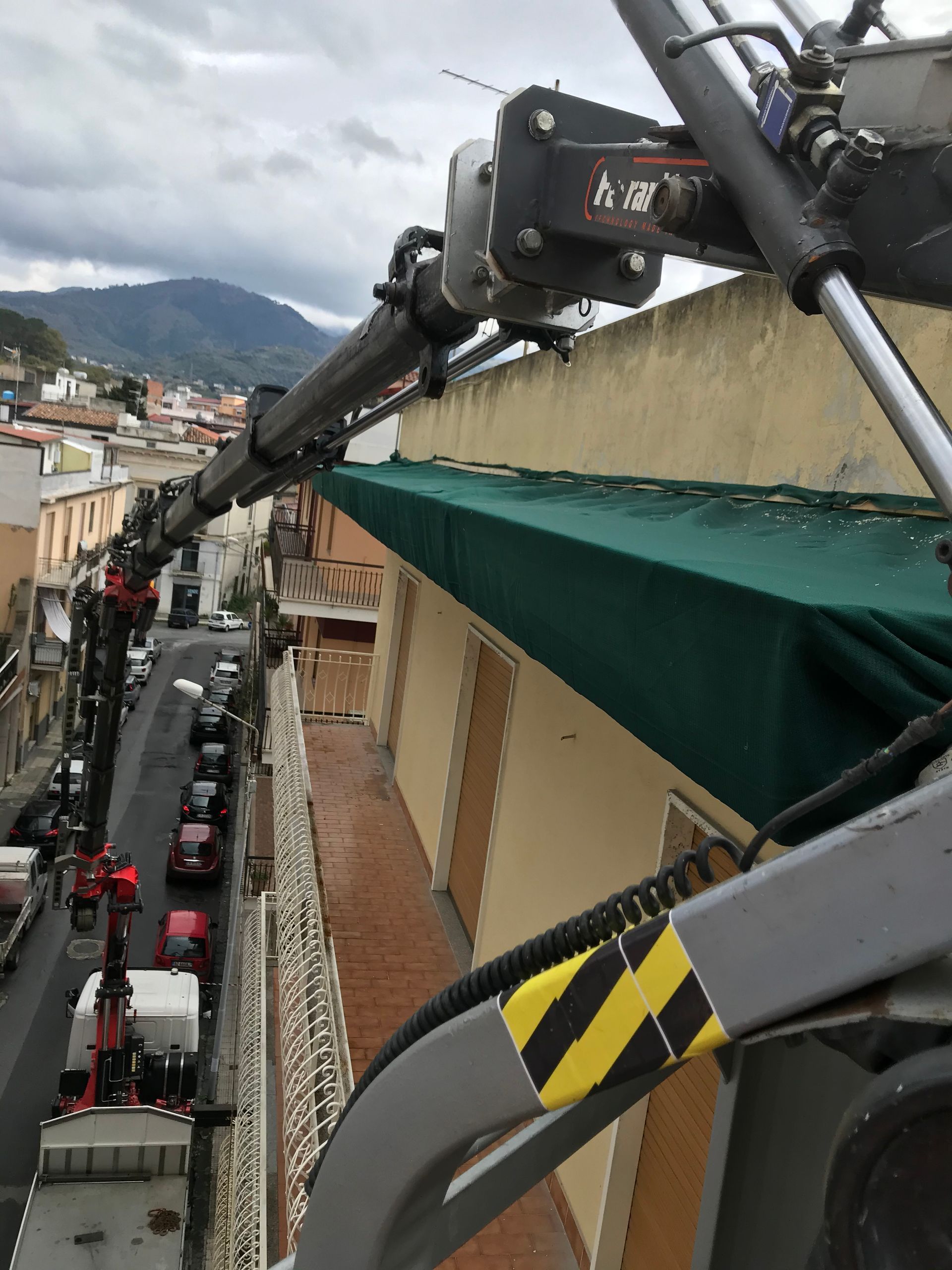 Una gru sta sollevando una tenda verde in cima a un edificio
