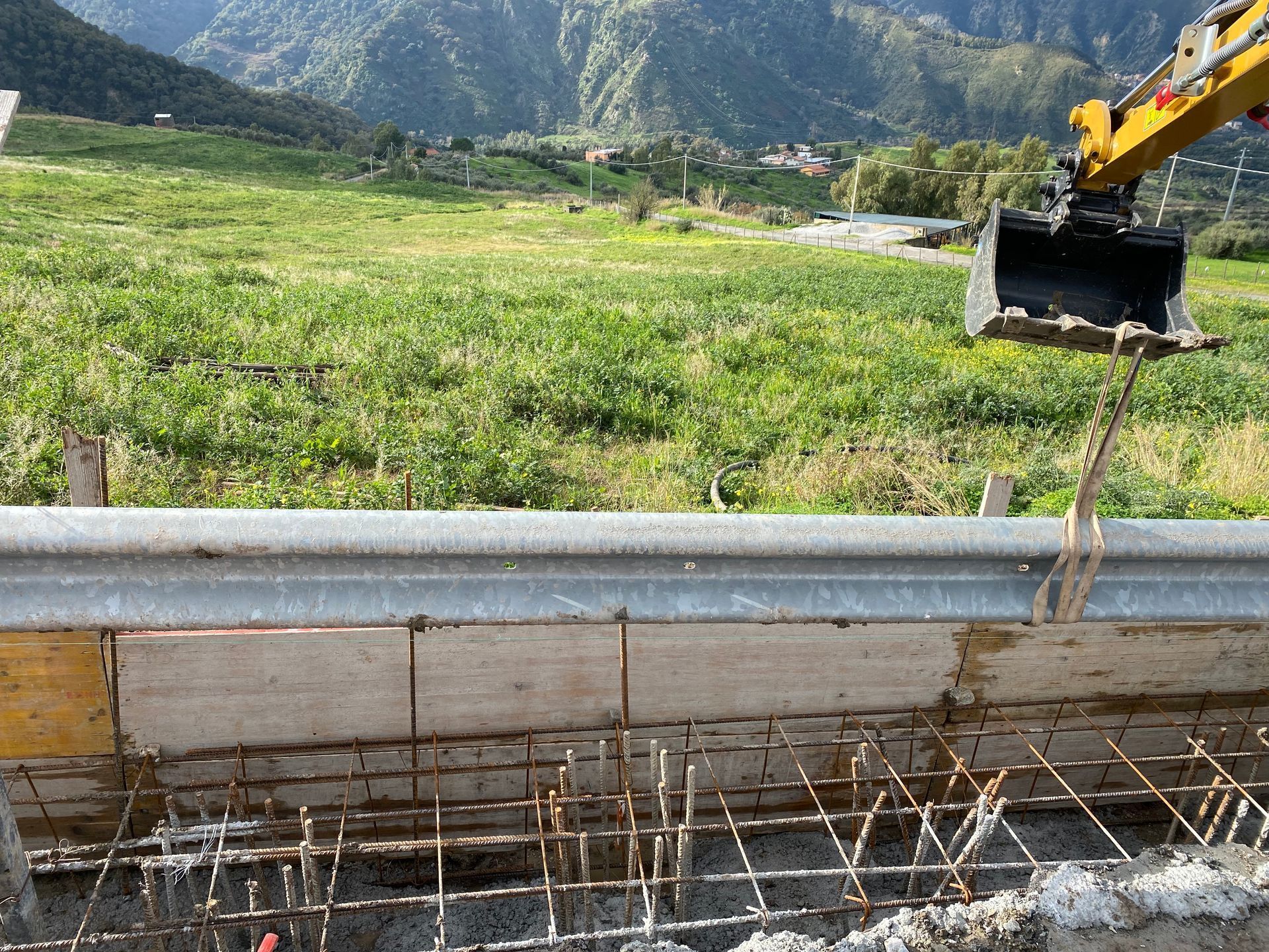 Un escavatore giallo sta scavando una buca in un campo.