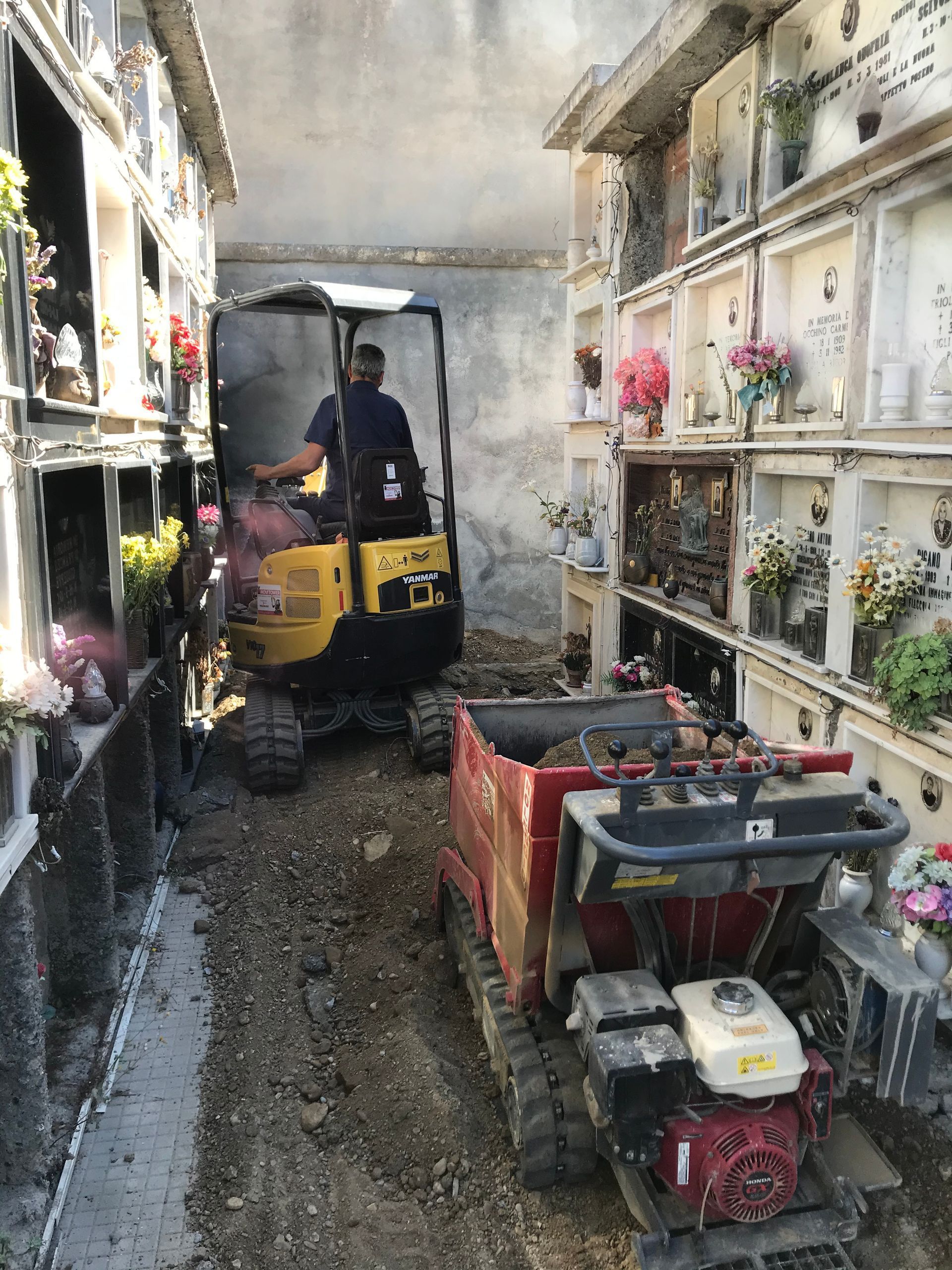 Un uomo sta guidando una ruspa gialla in un cimitero.