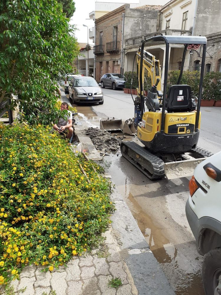 Un uomo è seduto sul marciapiede accanto a un escavatore giallo