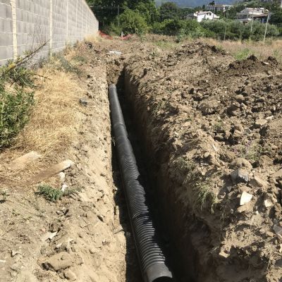 Un grande tubo nero viene installato in una trincea.