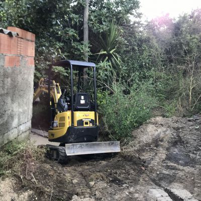 Un piccolo bulldozer giallo è parcheggiato su una strada sterrata