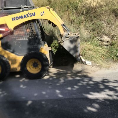 Un trattore giallo Komatsu sta guidando lungo una strada