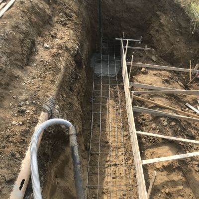 Un grande buco nel terreno da cui esce un tubo.