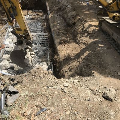 Un escavatore giallo sta scavando una buca nel terreno.