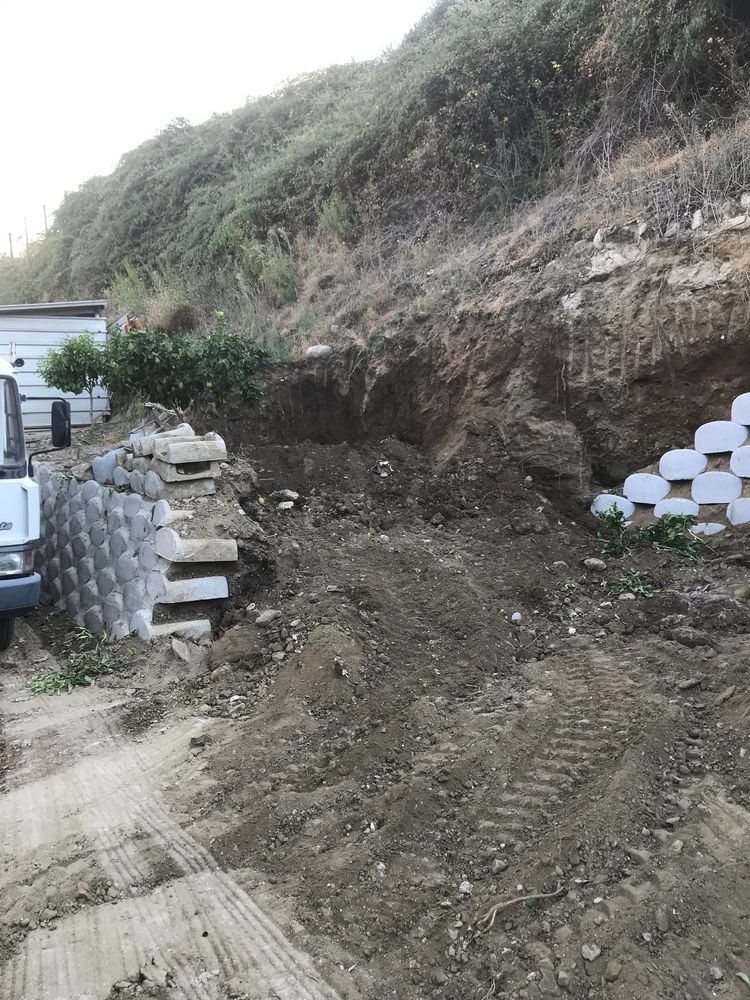 Un camion sta percorrendo una strada sterrata accanto a un mucchio di terra.