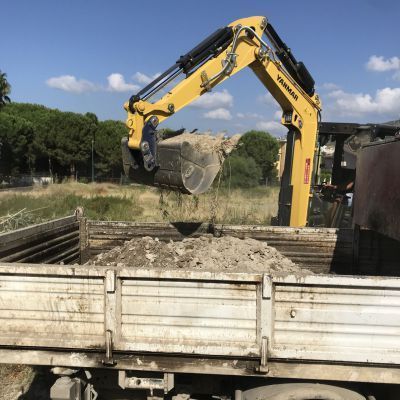 Un escavatore yanmar sta caricando terra su un camion