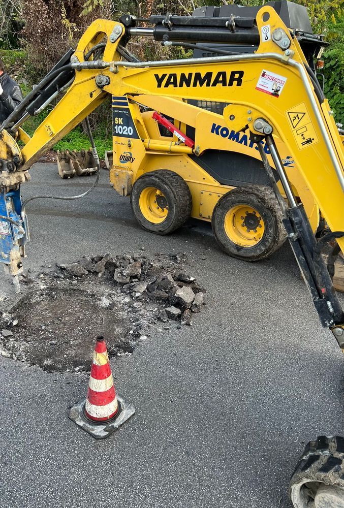 Un miniescavatore Yanmar giallo sta facendo una buca nella strada.
