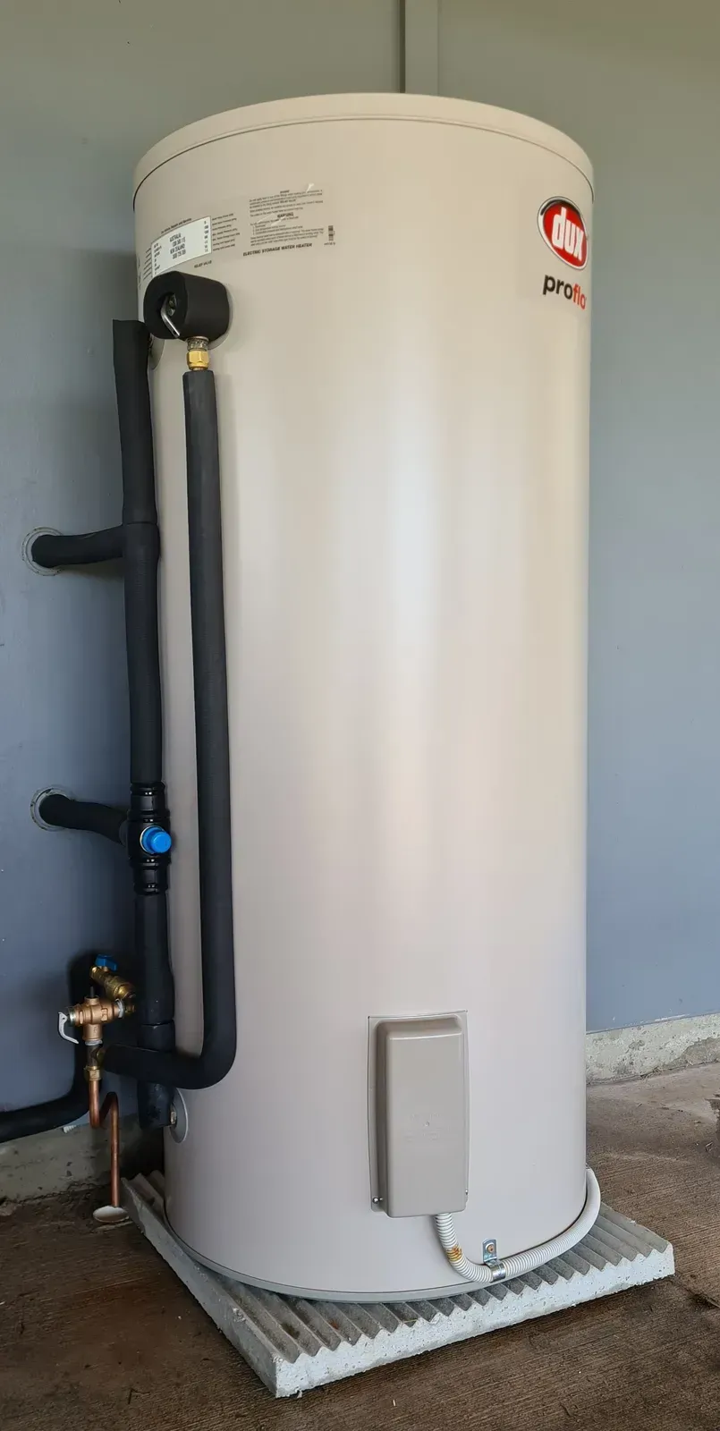 A Large, Beige Water Heater With Black Pipes and a Metal Base, Outdoors — 24/7 Hot Water in Caloundra, QLD