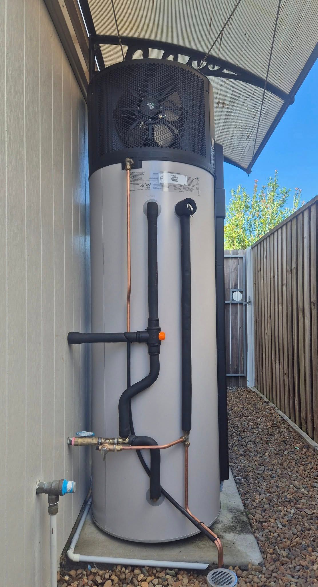 A Tall, Cylindrical Heat Pump Water Heater With Copper Pipes — 24/7 Hot Water in Valdora, QLD