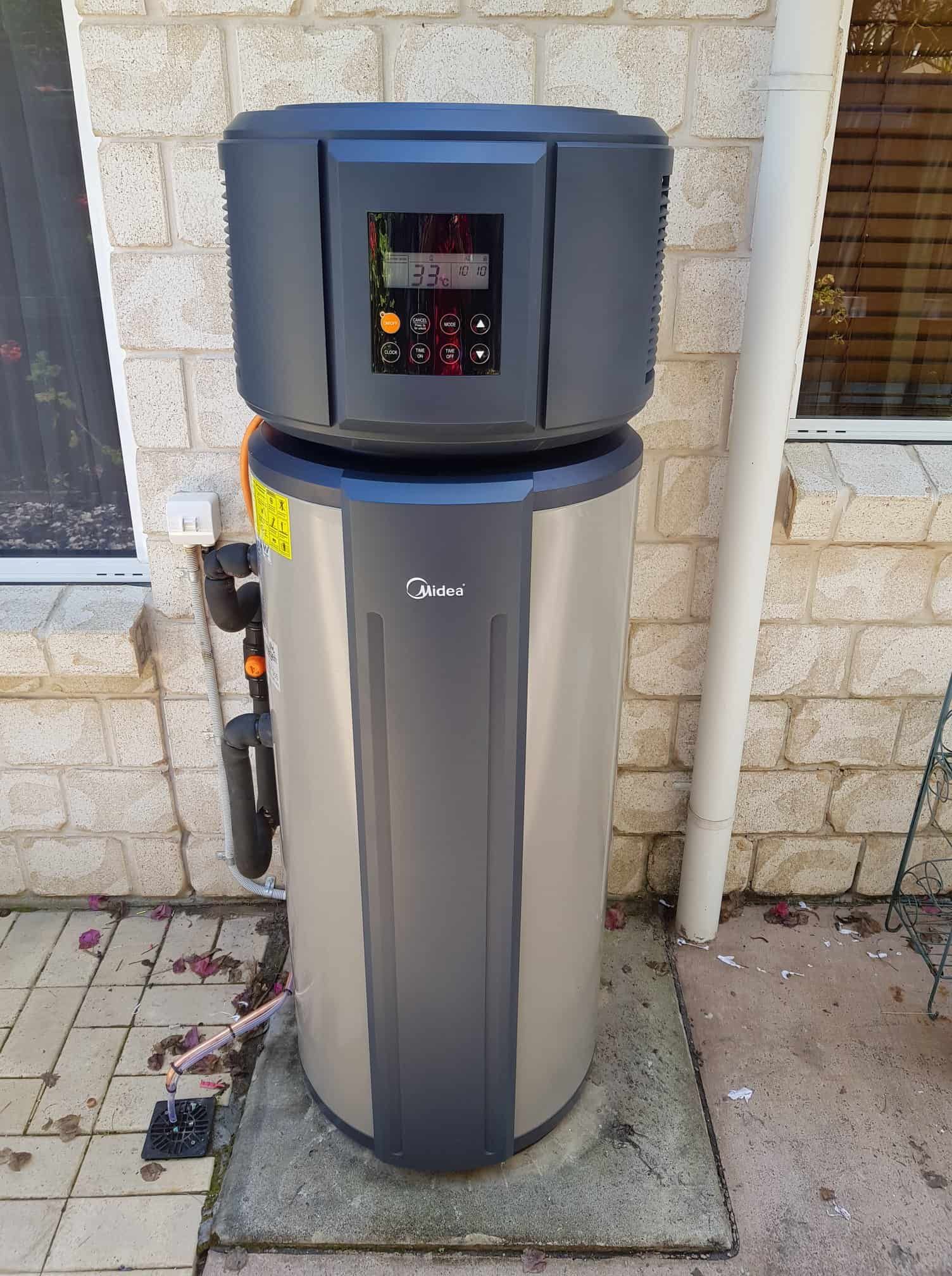 A tall, cylindrical hot water heater with a control panel is outside next to a brick wall. — 24/7 Hot Water in Valdora, QLD
