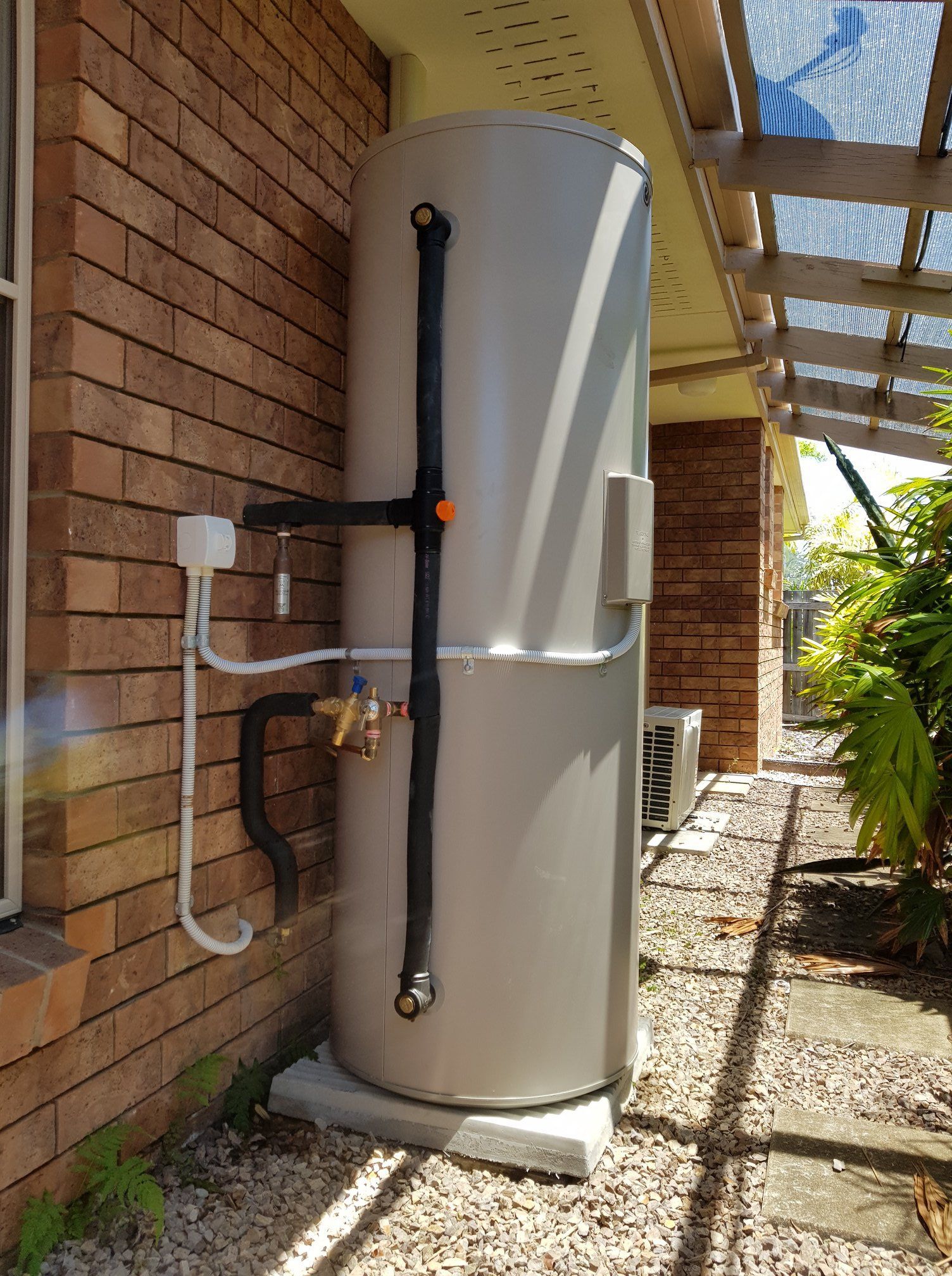 Gray Water Heater Tank Mounted on a Concrete Slab Against a Brick Wall — 24/7 Hot Water in Caloundra, QLD