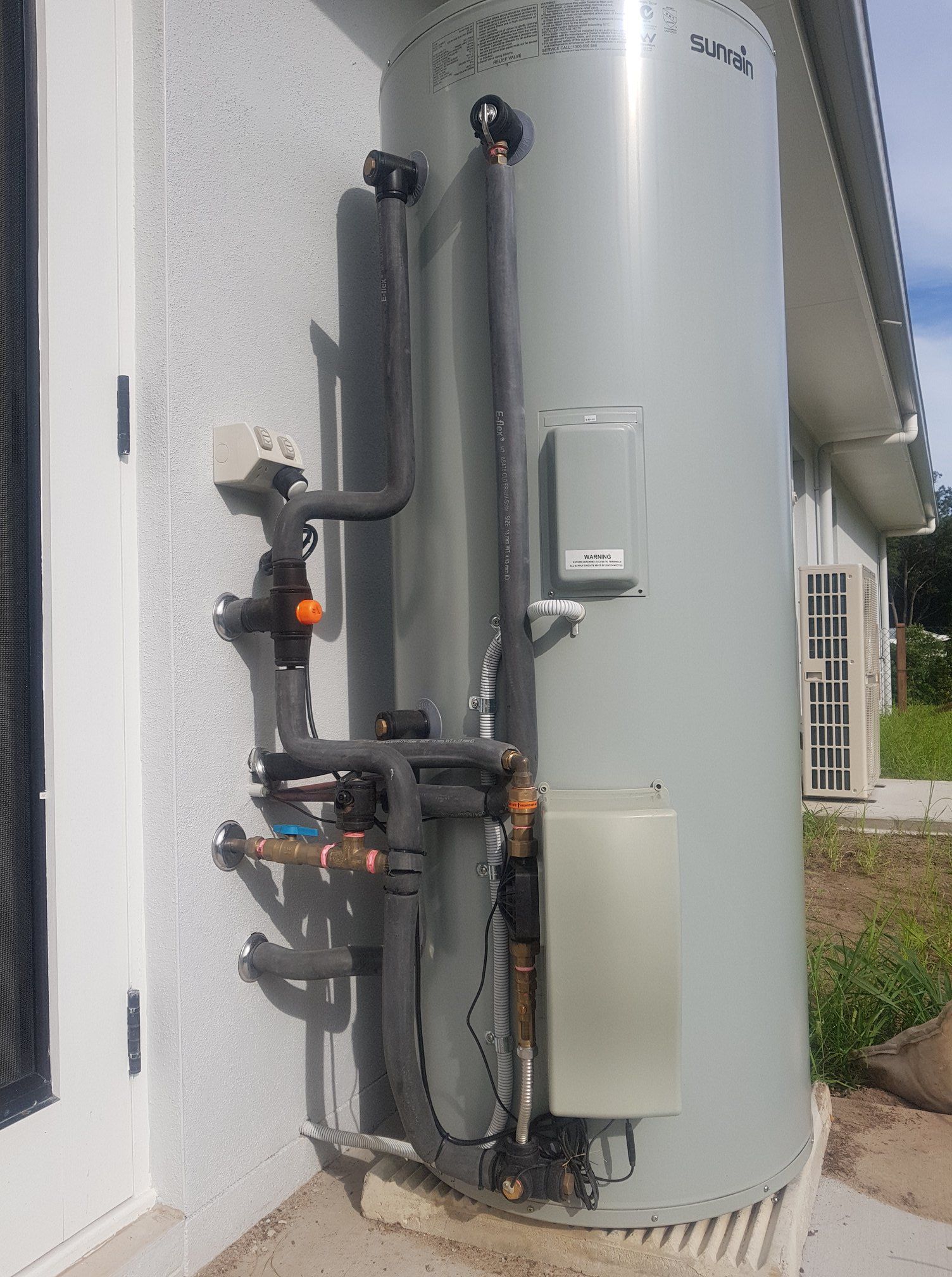 A Large, Gray Water Heater Attached to a White Building Exterior — 24/7 Hot Water in Valdora, QLD