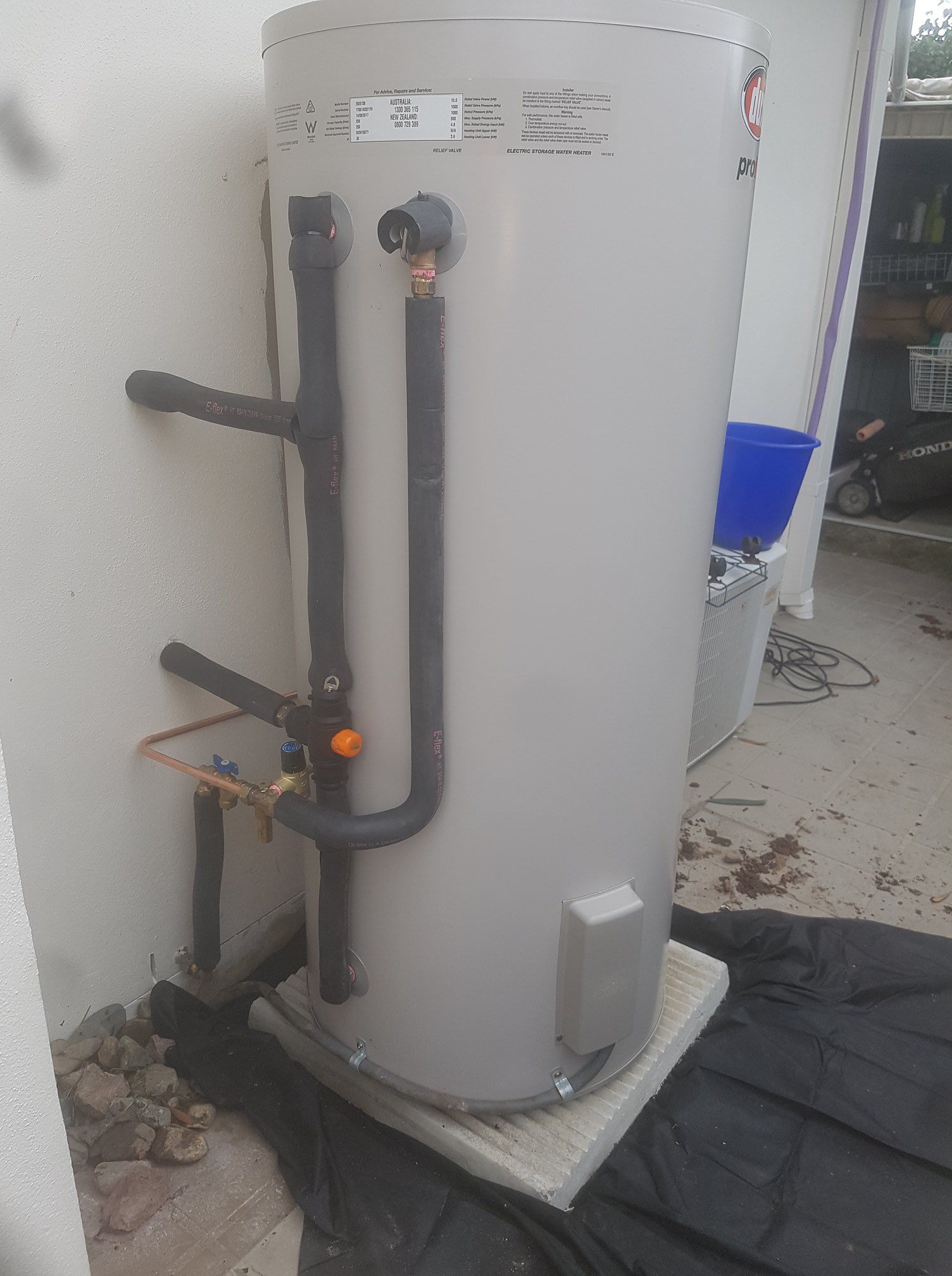 A Large, Gray Water Heater With Black Pipes and Copper Fittings Sits Outside — 24/7 Hot Water in Caloundra, QLD