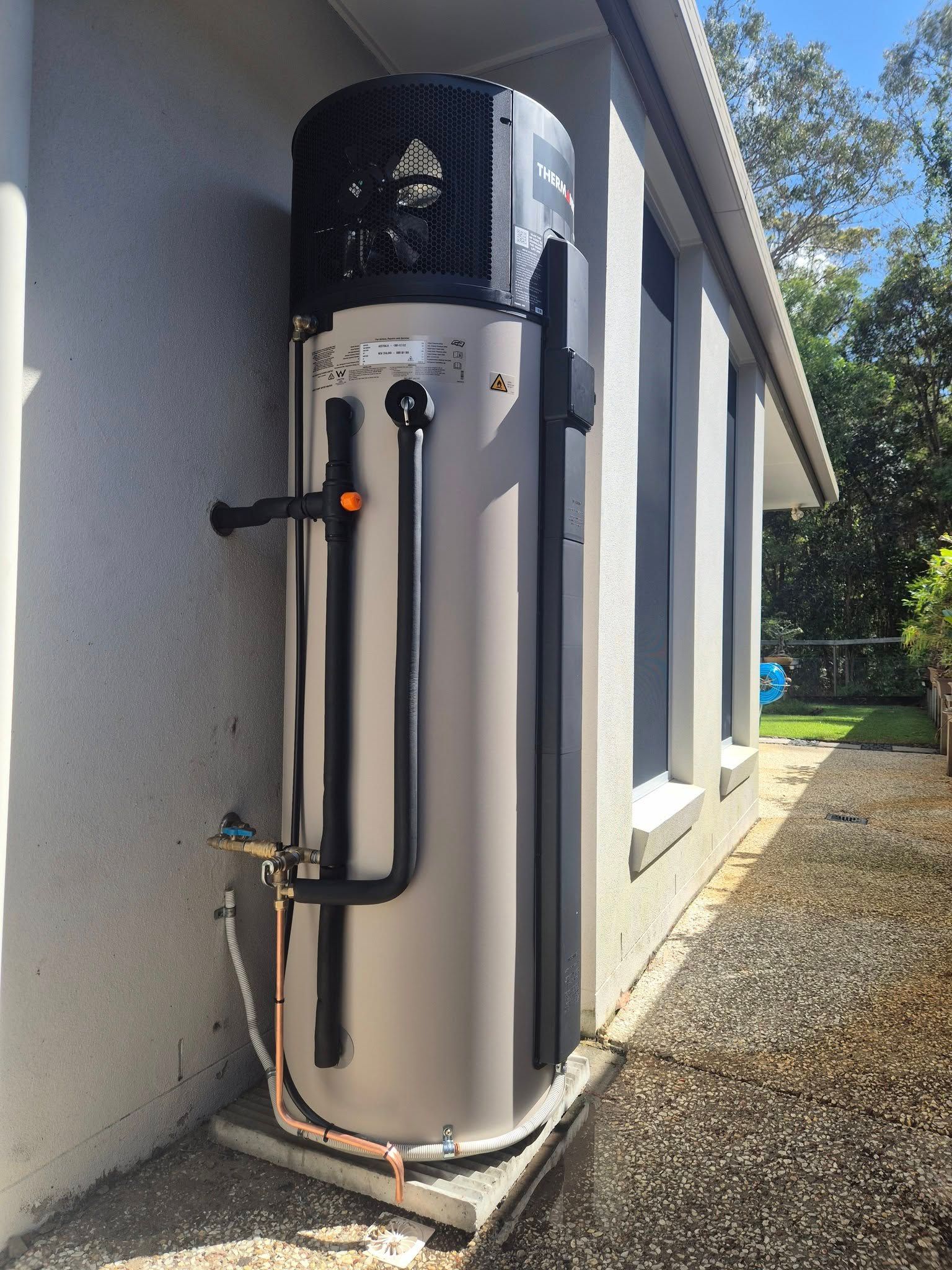 Heat Pump Water Heater Mounted on a Concrete Slab Against a Building Wall — 24/7 Hot Water in Valdora, QLD