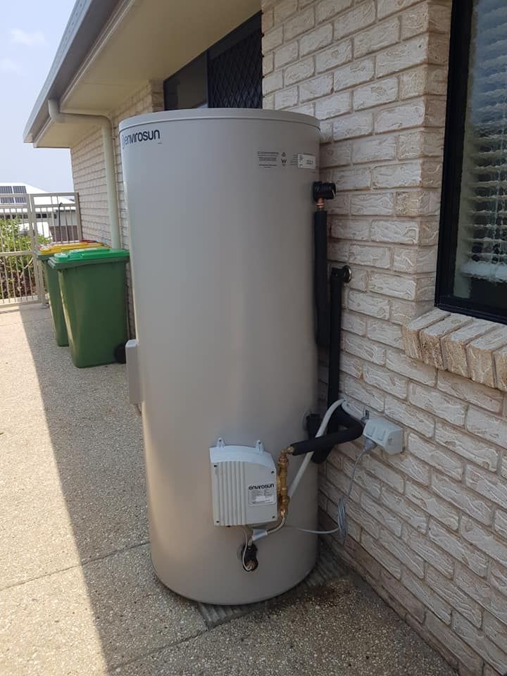 Large gray water heater tank mounted on a brick wall next to a window; concrete patio. — 24/7 Hot Water in Maroochydore, QLD