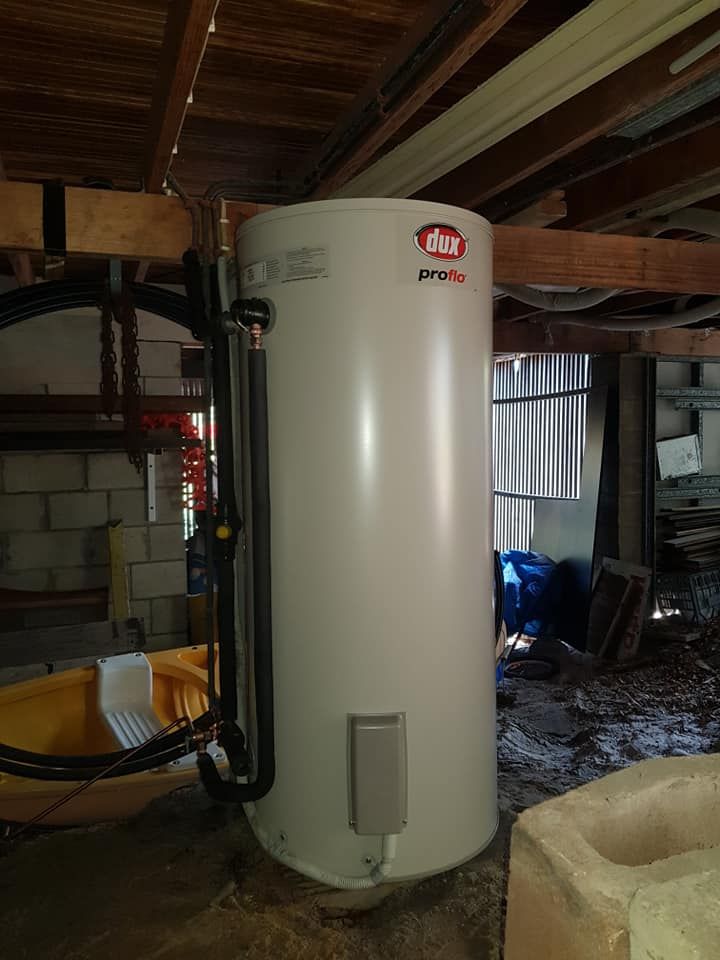 Gray cylindrical water tank on a wooden deck next to a house and a fence. — 24/7 Hot Water in Valdora, QLD