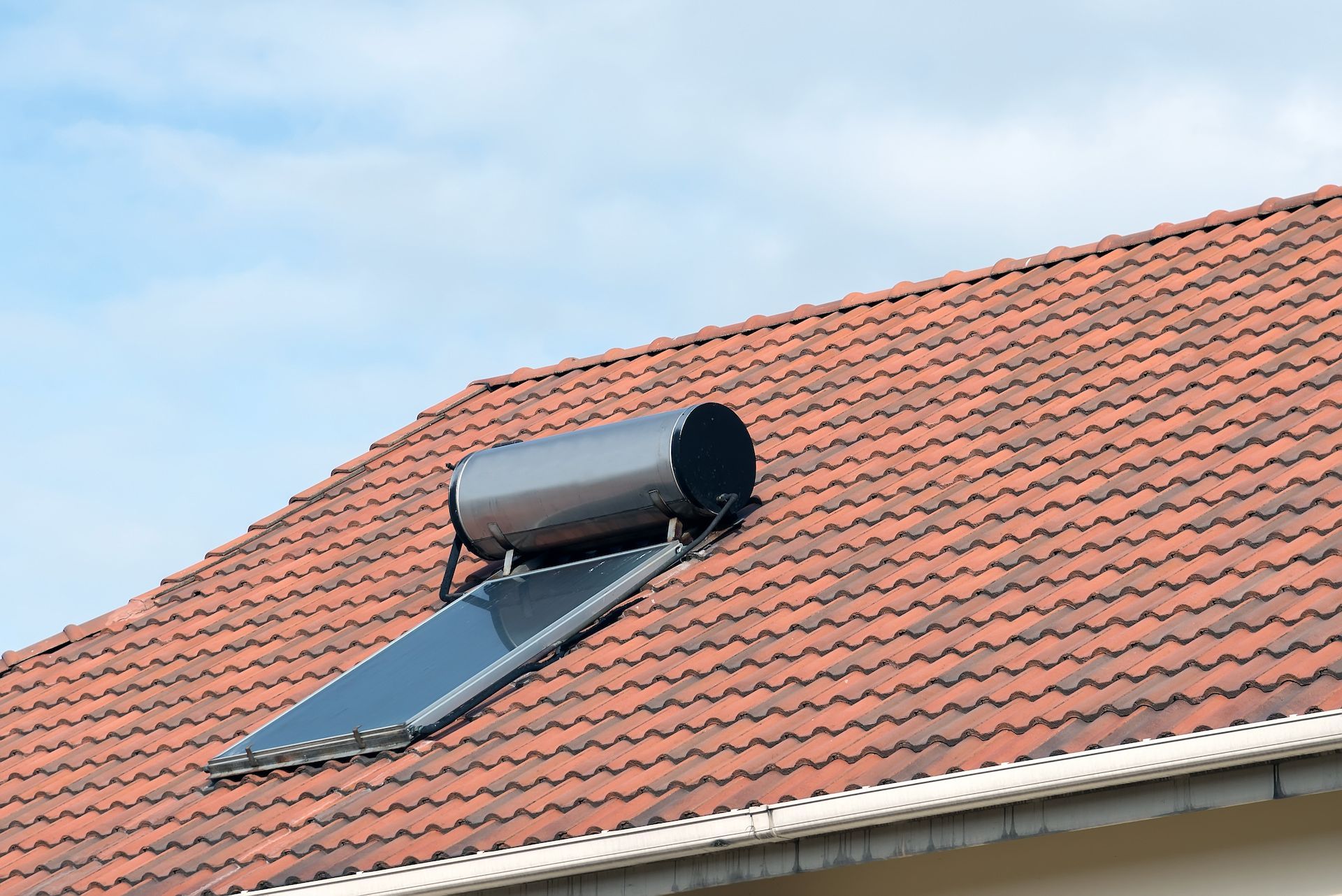 Solar Water Heater on a Red Tile Roof Against a Blue Sky — 24/7 Hot Water in Maroochydore, QLD