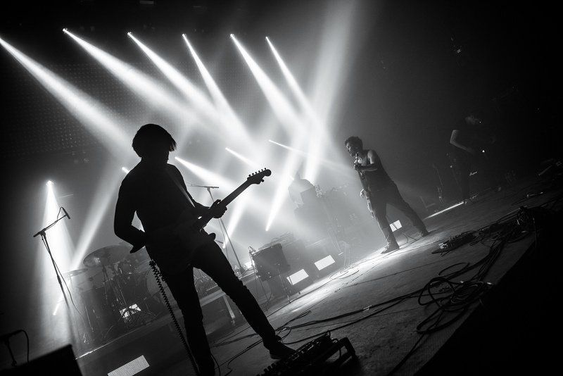 a black and white photo of a man playing a guitar on a stage .