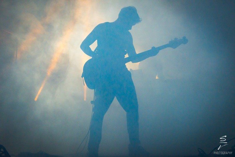 a silhouette of a man playing a guitar on a stage .