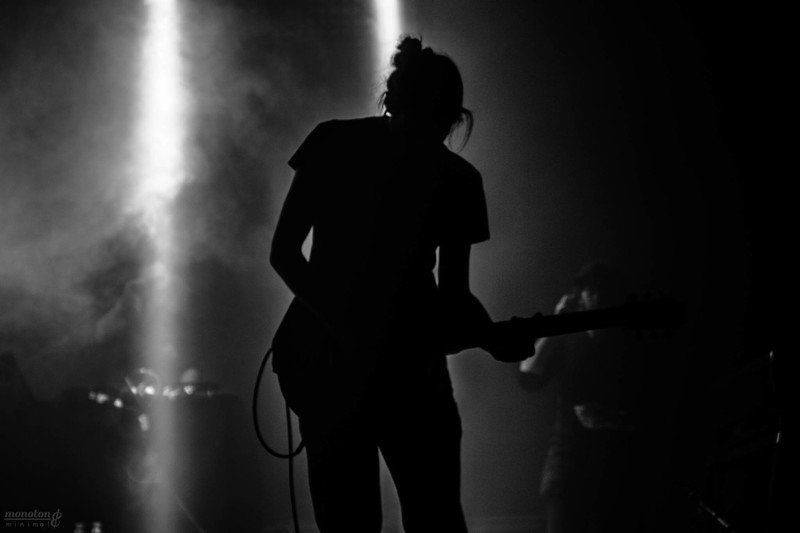 a black and white photo of a woman playing a guitar on stage .