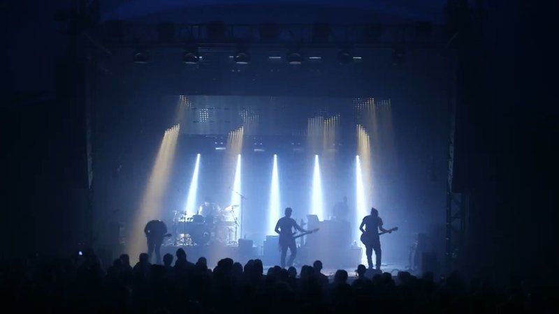 a group of people are playing guitars on a stage in front of a crowd .