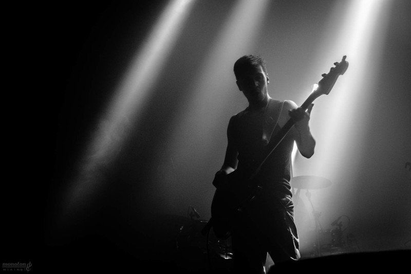 a man without a shirt is playing a guitar in a dark room .