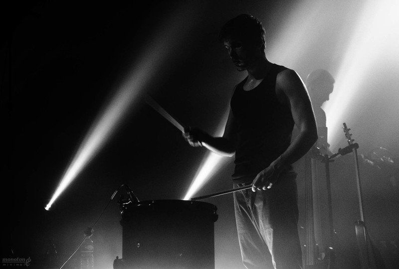 a man is playing drums on a stage in a black and white photo .